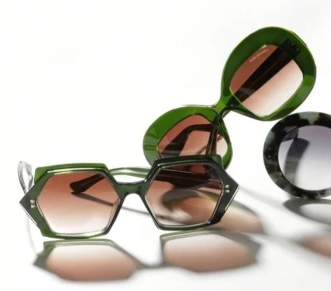 Three sunglasses with colored frames and lenses; green and tortoise shell on a white surface.