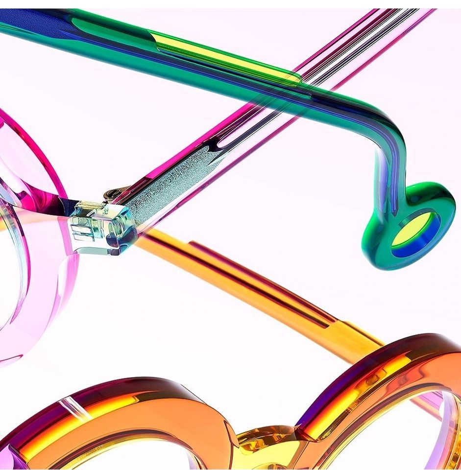 Close-up of three pairs of colorful glasses: pink, green, and orange, with iridescent sheen.