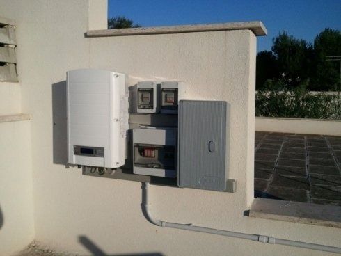 Apparecchiature a pannelli solari, tra cui un inverter, contatori e una scatola elettrica grigia.