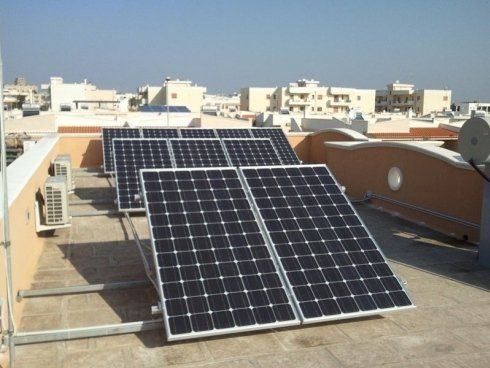 Pannelli solari installati su un tetto in un ambiente urbano soleggiato.