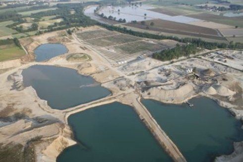 Vista aerea di una cava di sabbia con diverse fosse piene d'acqua e terrapieni circostanti.