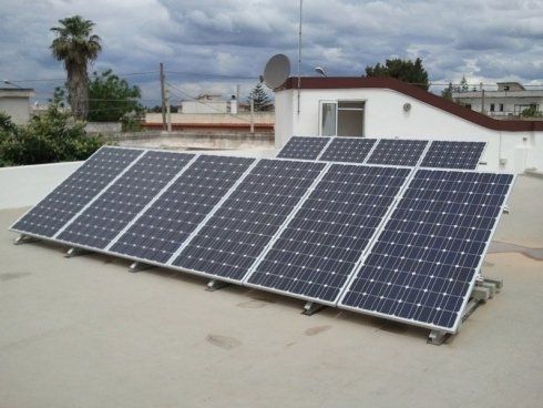 Pannelli solari installati su un tetto bianco sotto un cielo nuvoloso.