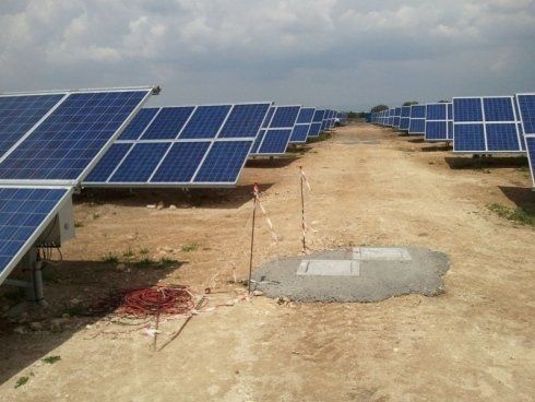 Pannelli solari in un campo sotto un cielo nuvoloso. File di pannelli blu sono rivolte verso l'osservatore.