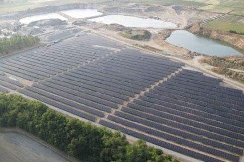 Vista aerea di un grande impianto di pannelli solari accanto a stagni e una cava.