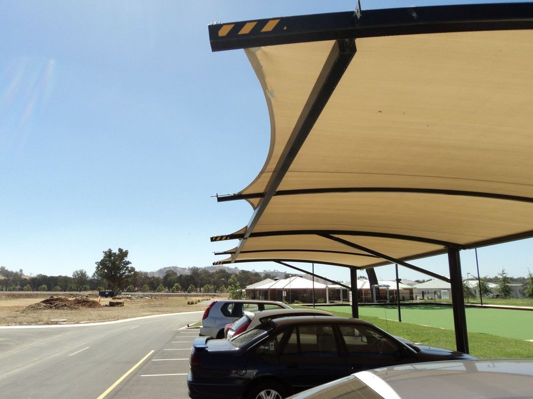 A Beige Fabric Shade Structure Covers a Line of Parked Cars — The Gazebo and Shade Centre in Jindera, NSW