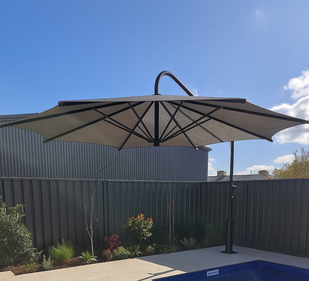Backyard patio with a large patio umbrella, fence, plants, and blue pool under a clear sky — The Gazebo and Shade Centre in Corowa, NSW