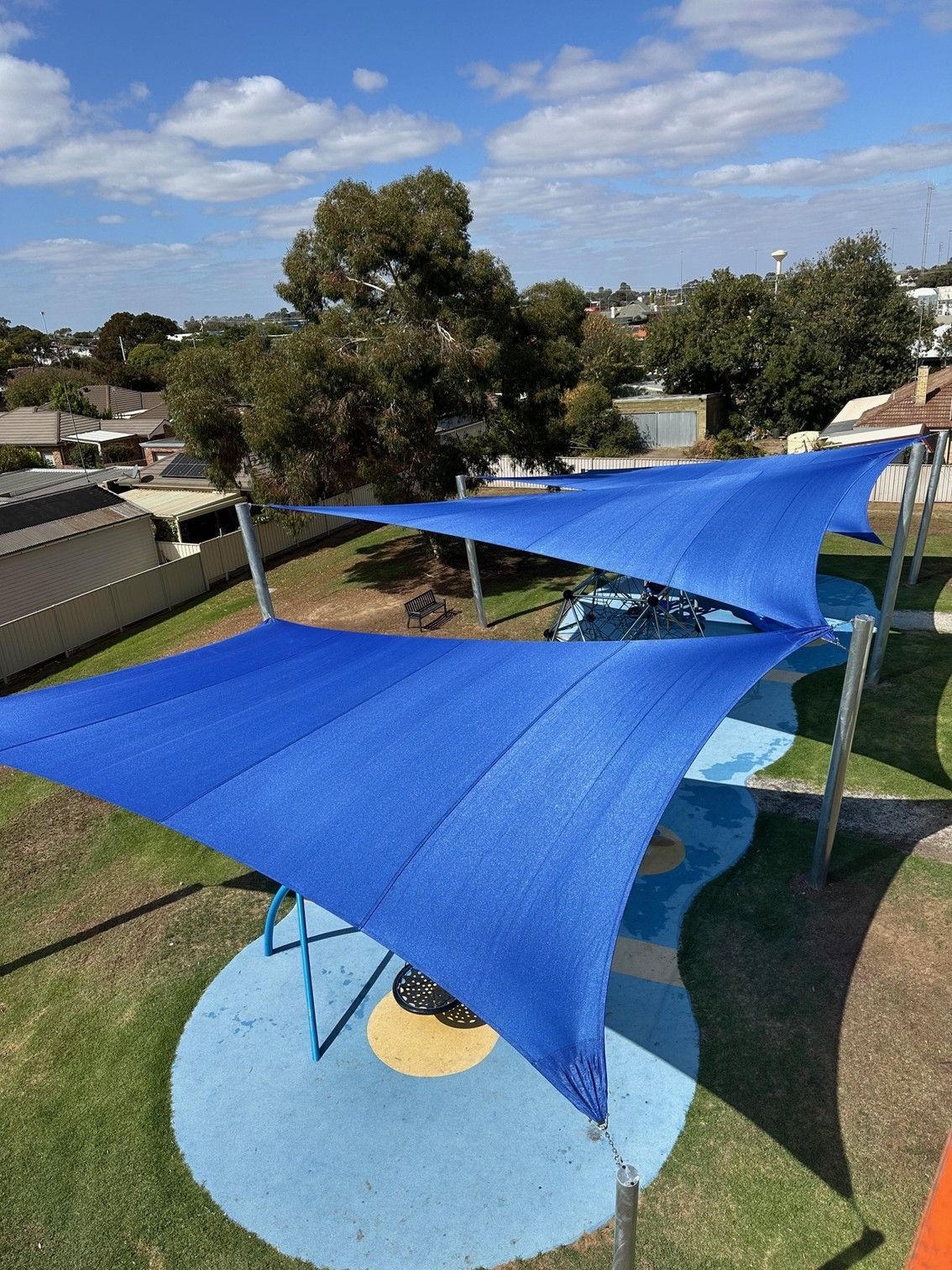 Blue shade sails over a backyard patio and lawn on a sunny day — The Gazebo and Shade Centre in Yarrawonga, VIC