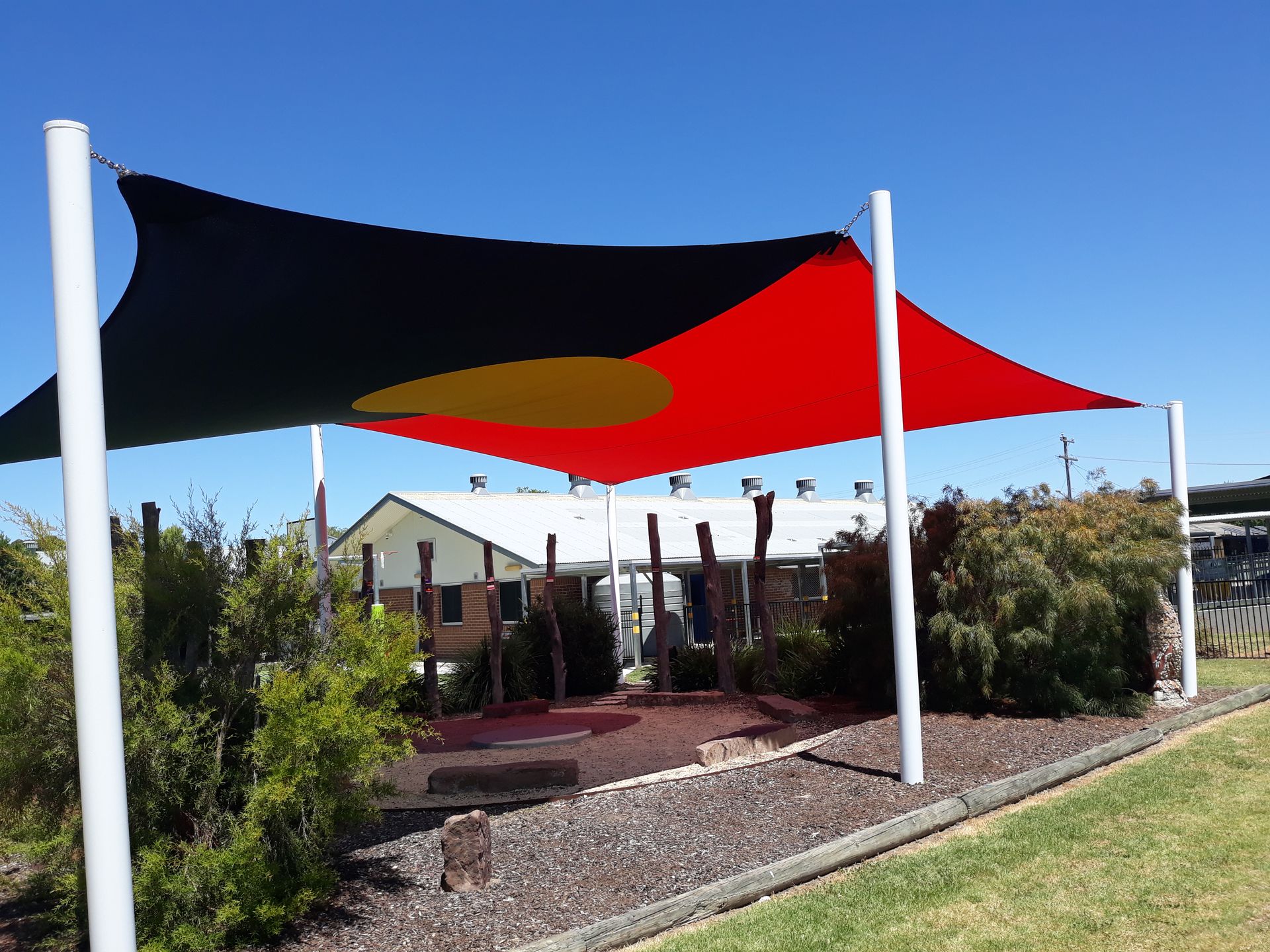 Outdoor shade sails in black and red over a patio in a landscaped yard — The Gazebo and Shade Centre in Jindera, NSW