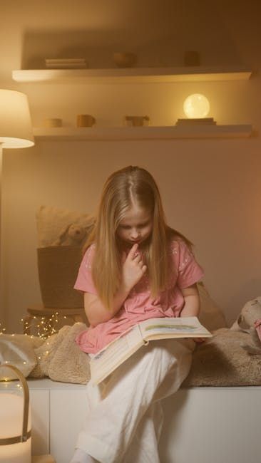 Vrouw in roze zit op een bed en leest een boek in een zacht verlichte slaapkamer.