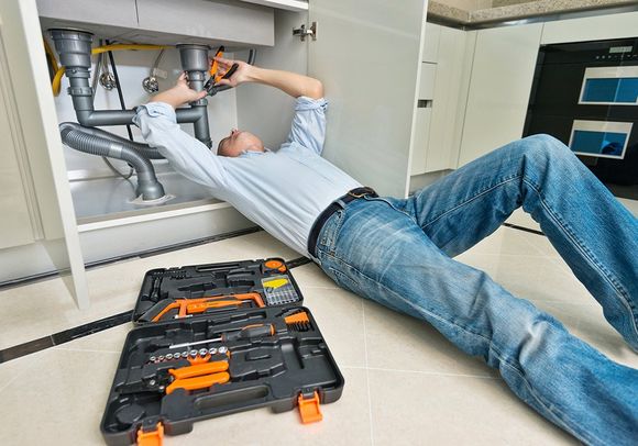 Man Repairing Sink Pipe in the Kitchen — El Paso, TX — Plumbers Drain Cleaning