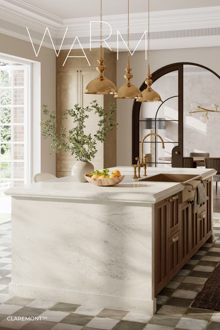 Warm-toned kitchen with marble island, brass fixtures, wooden cabinetry, and gold pendant lights.