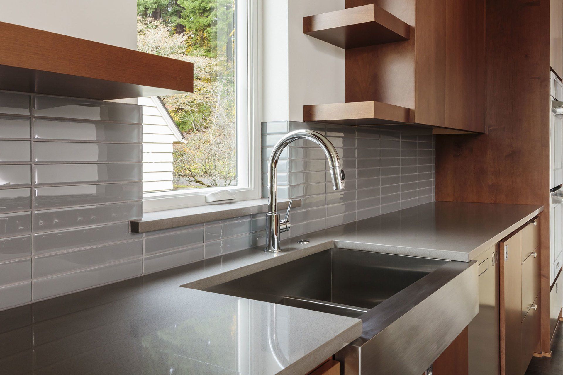 Bright white kitchen with light wood floors, island, stainless steel appliances, and gray walls.