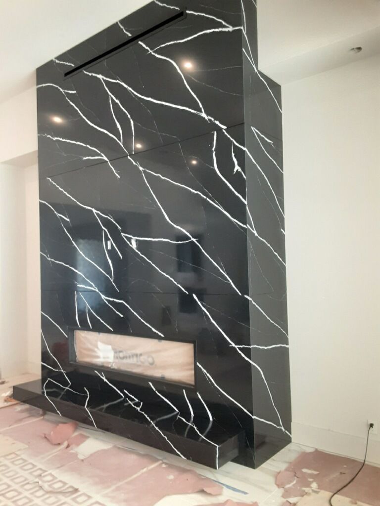 Black marble fireplace with white veining; modern design, against a white wall.