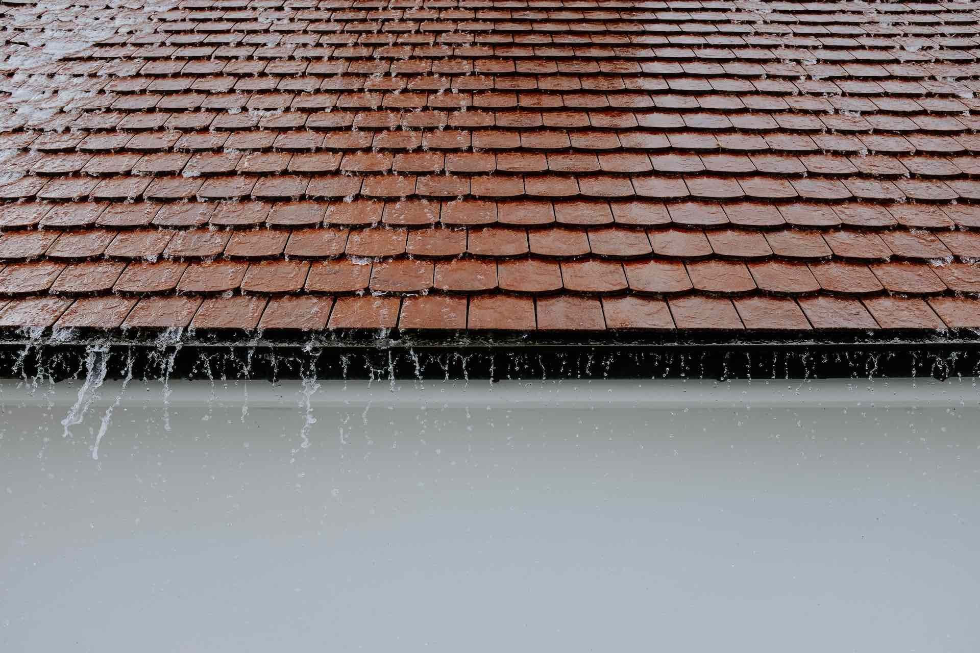 Rain is falling on a red tiled roof.