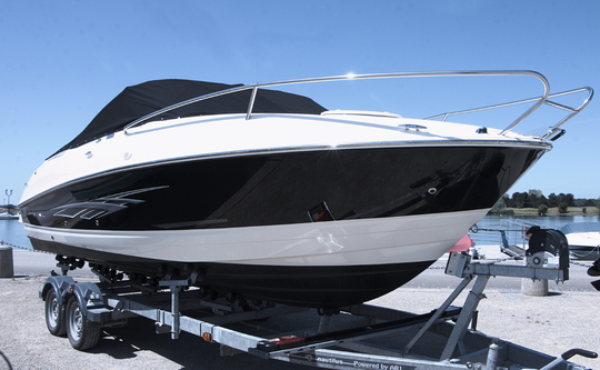 A boat is sitting on a trailer next to a body of water.