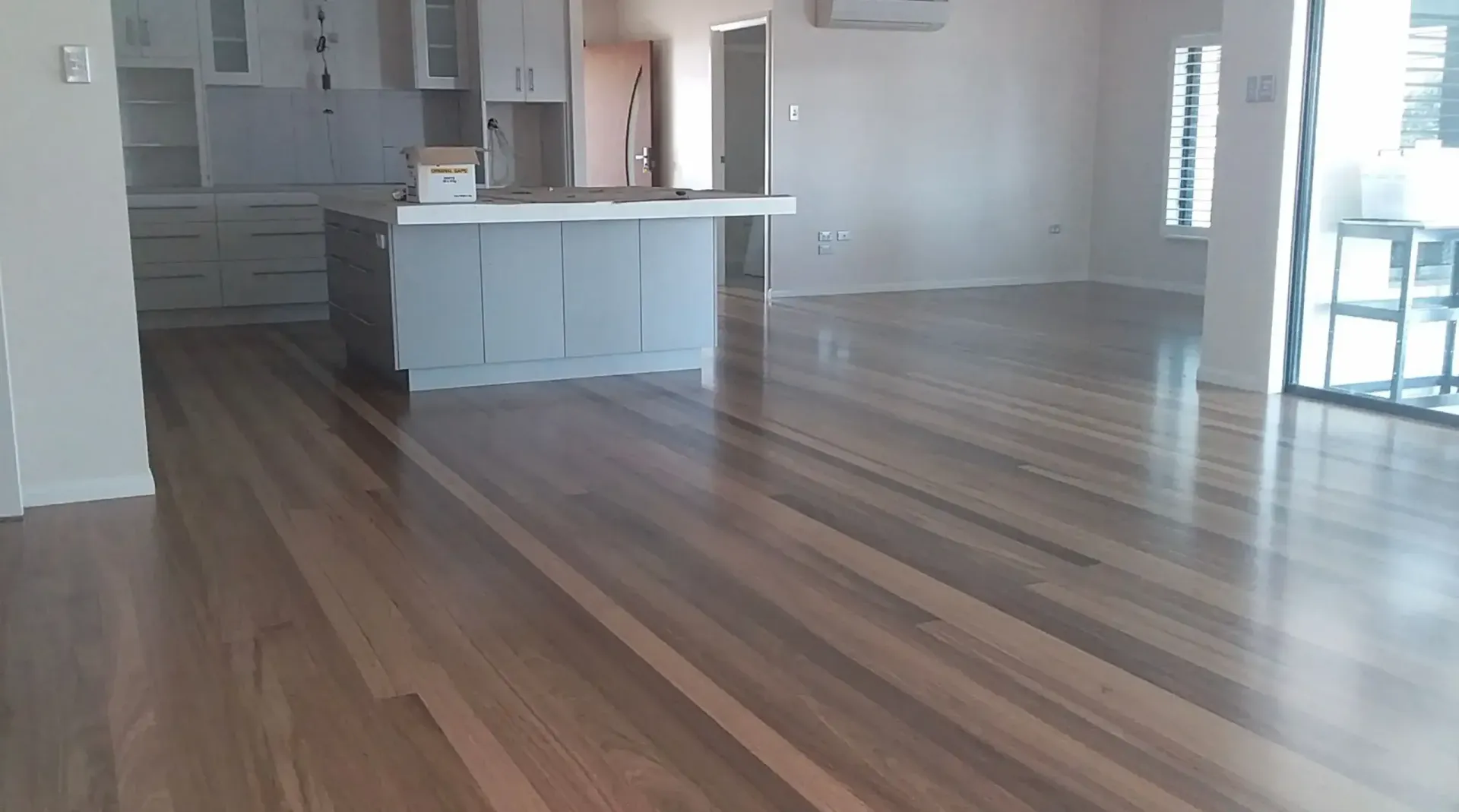 A Kitchen With A Wooden Floor And White Cabinets — Dale Dow Floor Sanding In Kirwan, QLD
