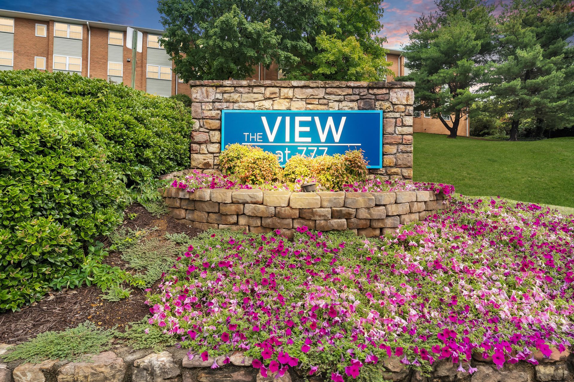 A sign for the view is surrounded by flowers and bushes.