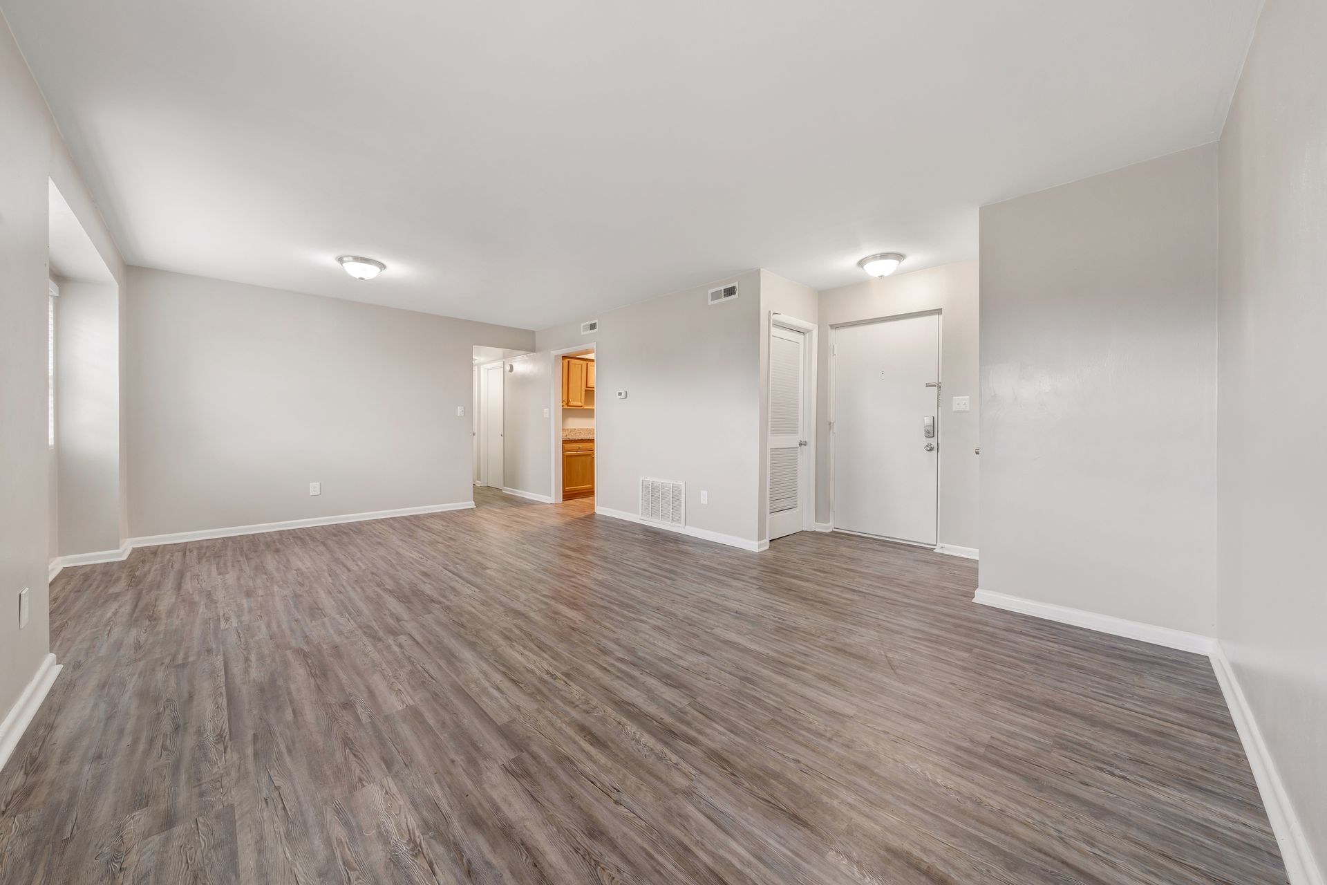 An empty living room with hardwood floors and white walls.