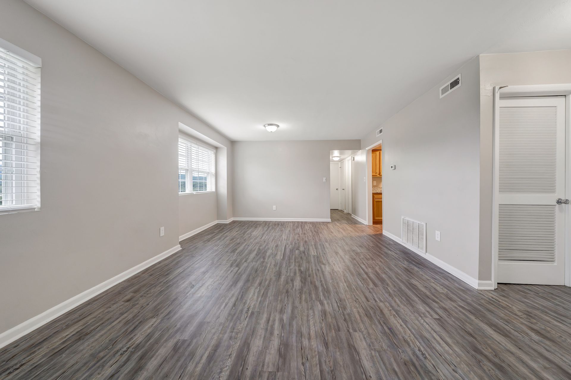 An empty living room with hardwood floors and white walls.