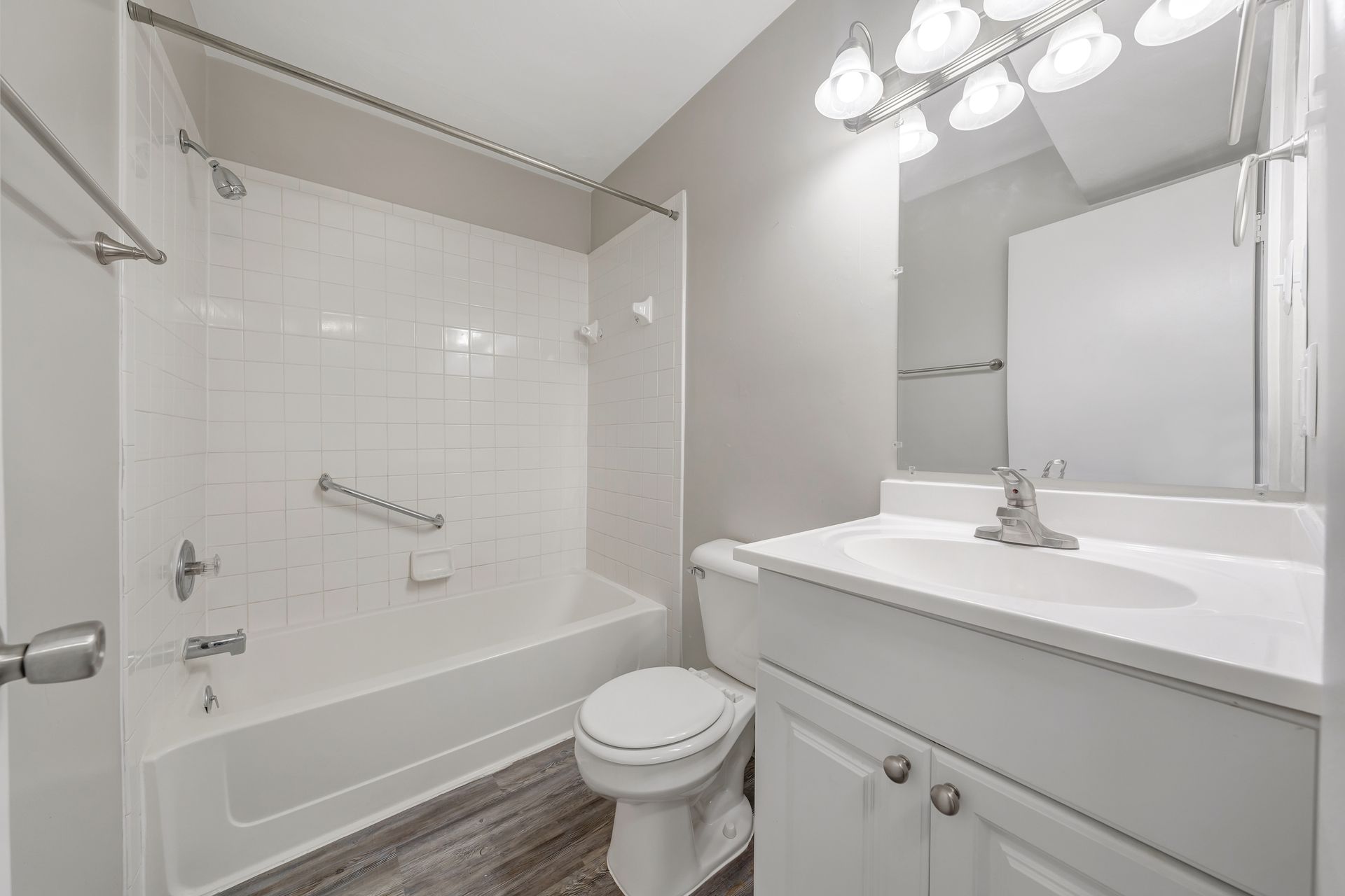 A bathroom with a toilet , sink , bathtub and mirror.