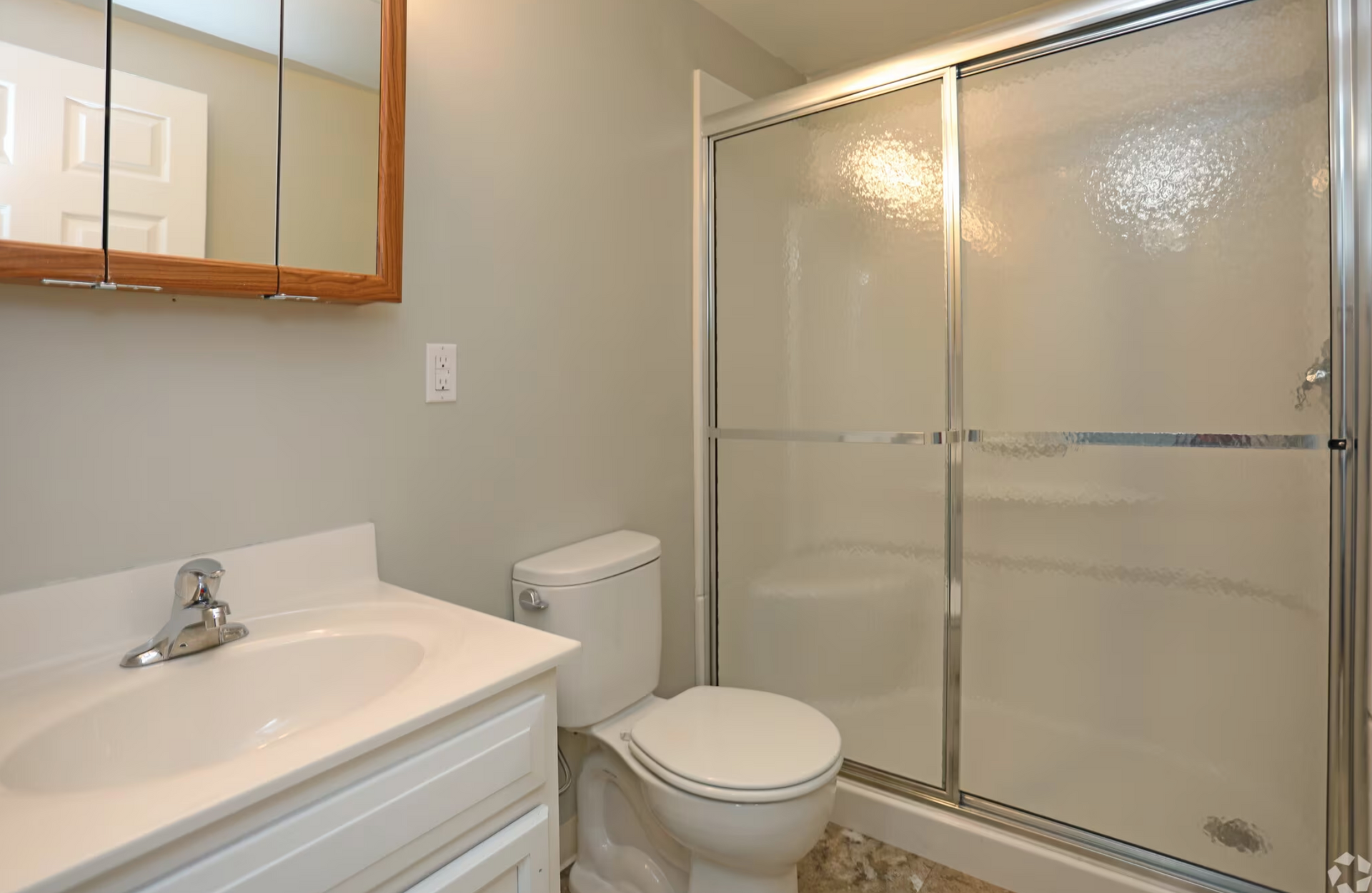 A bathroom with a toilet , sink and shower.