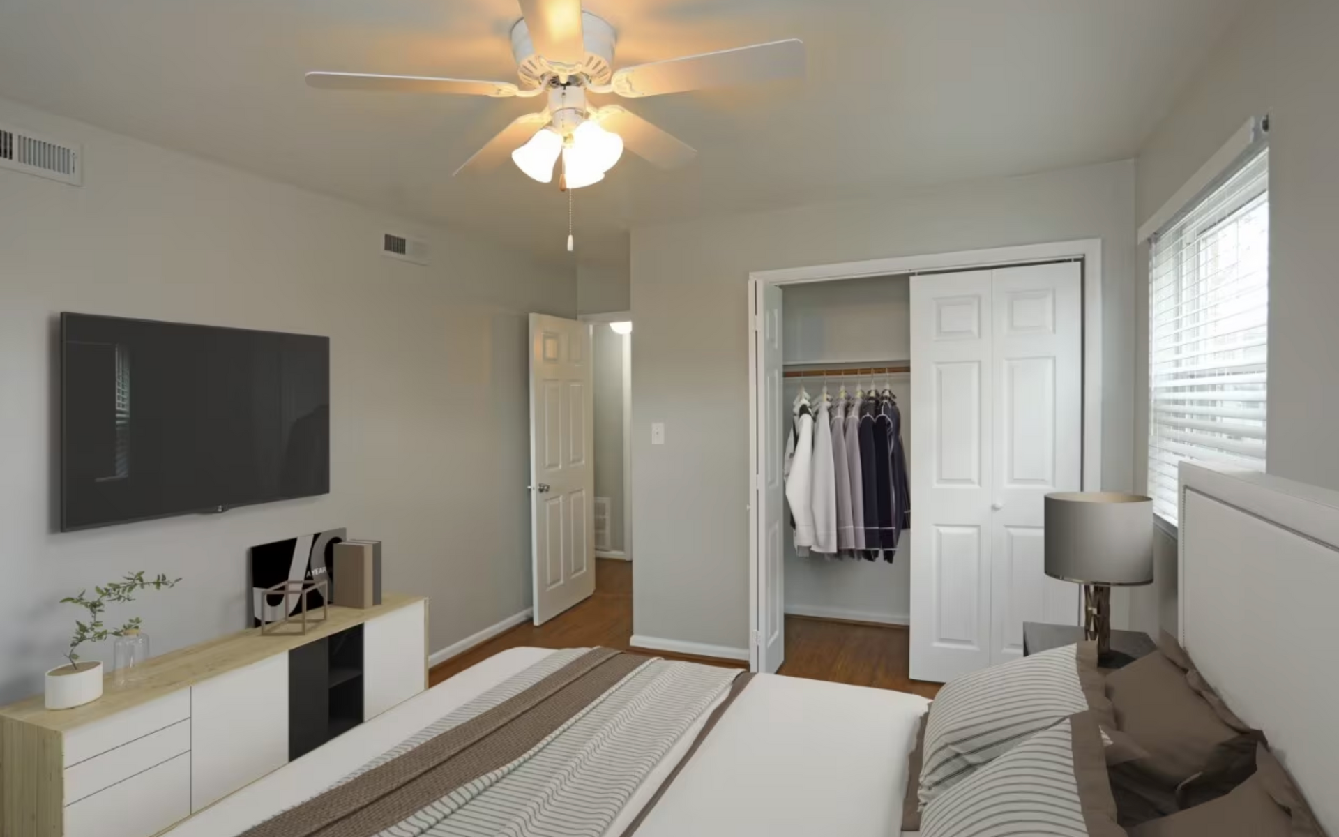 A bedroom with a bed , television , closet and ceiling fan.