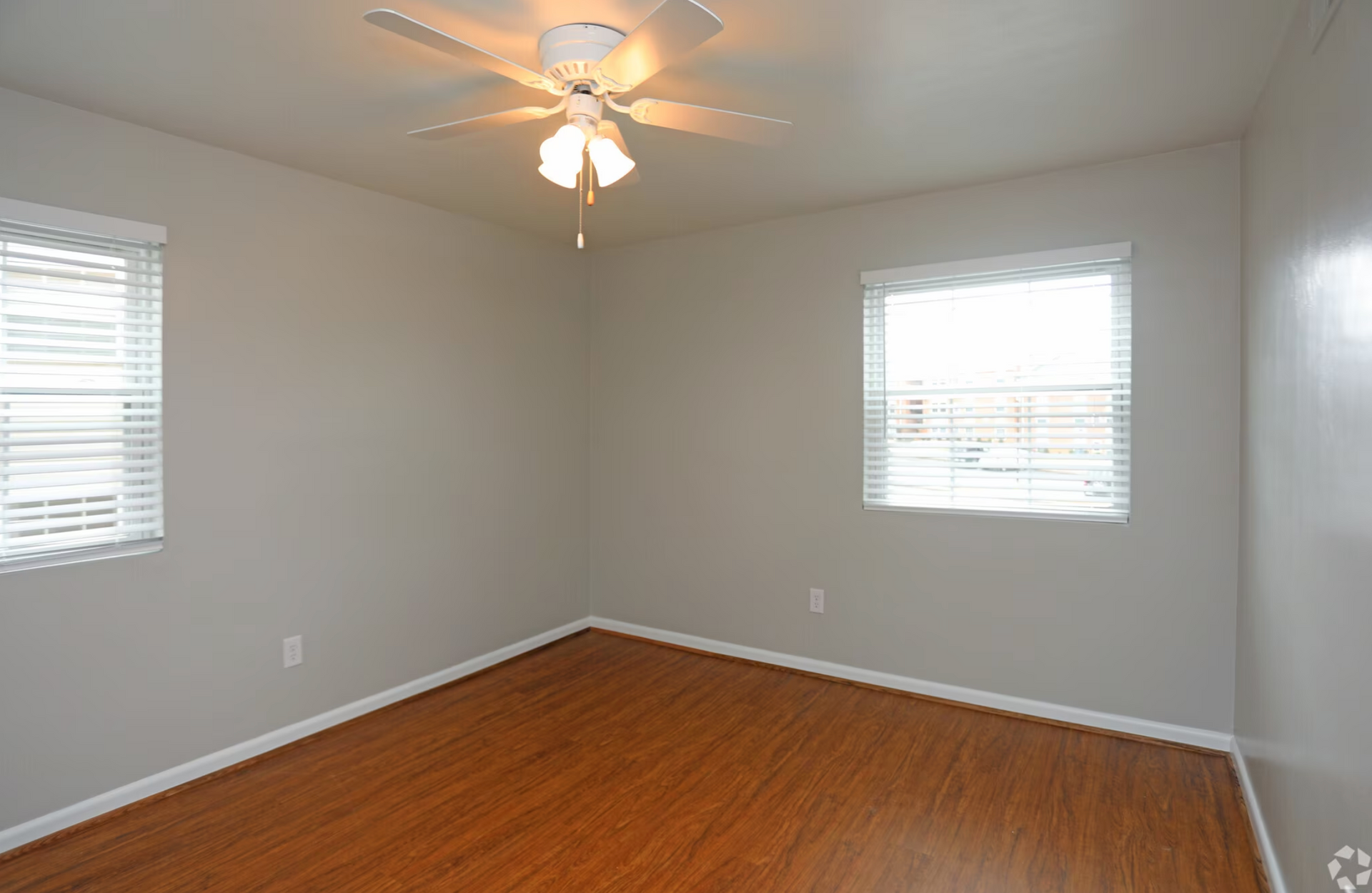 An empty bedroom with hardwood floors and a ceiling fan.