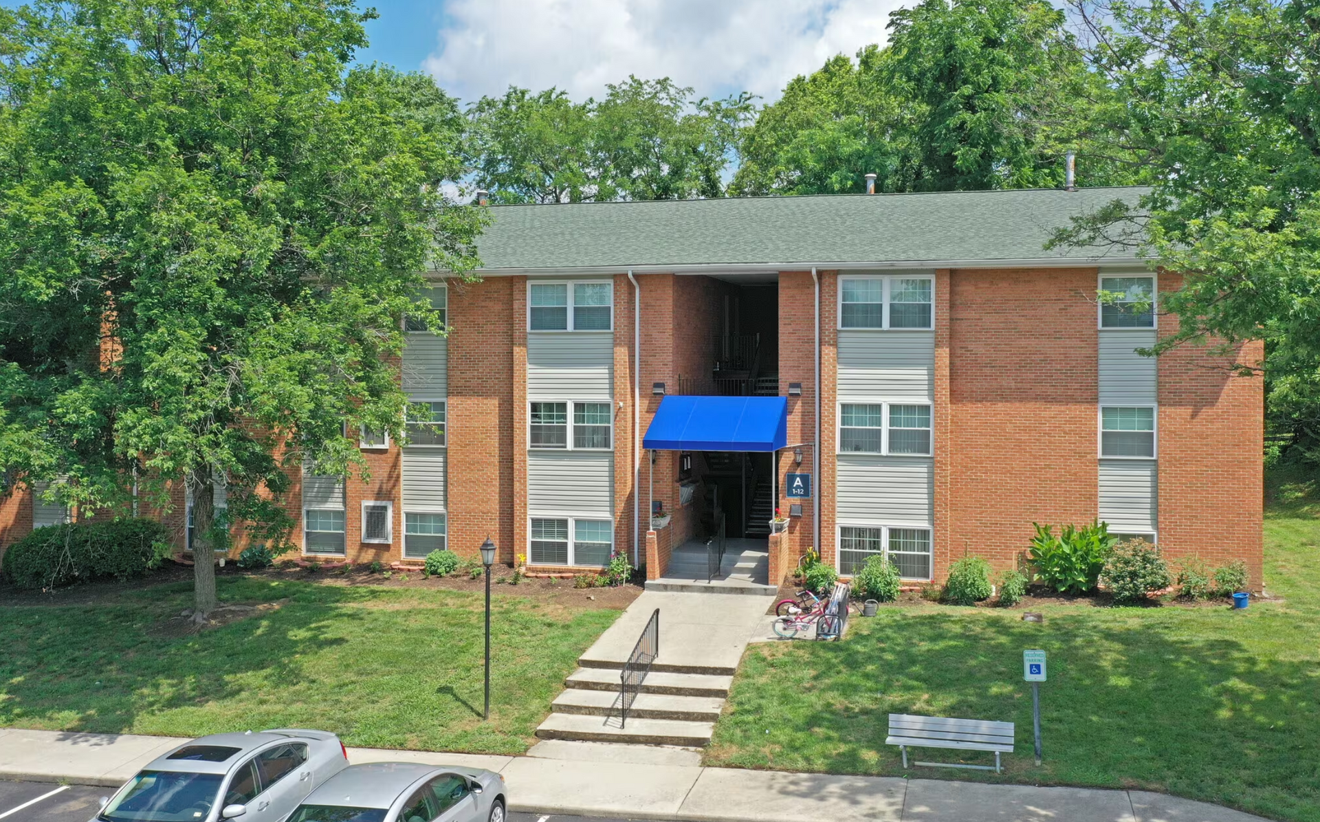 An aerial view of a brick apartment building with cars parked in front of it.