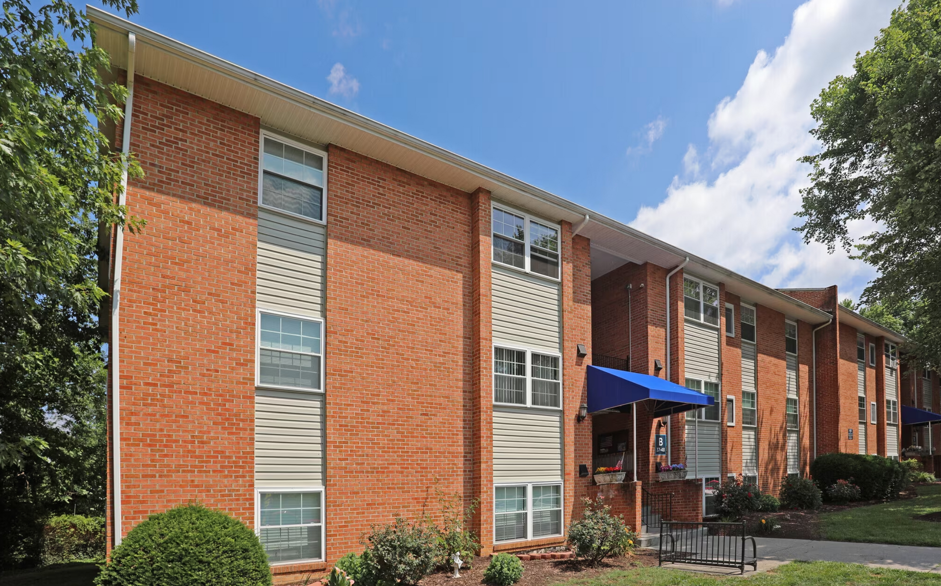A large brick apartment building with a blue awning over the entrance.
