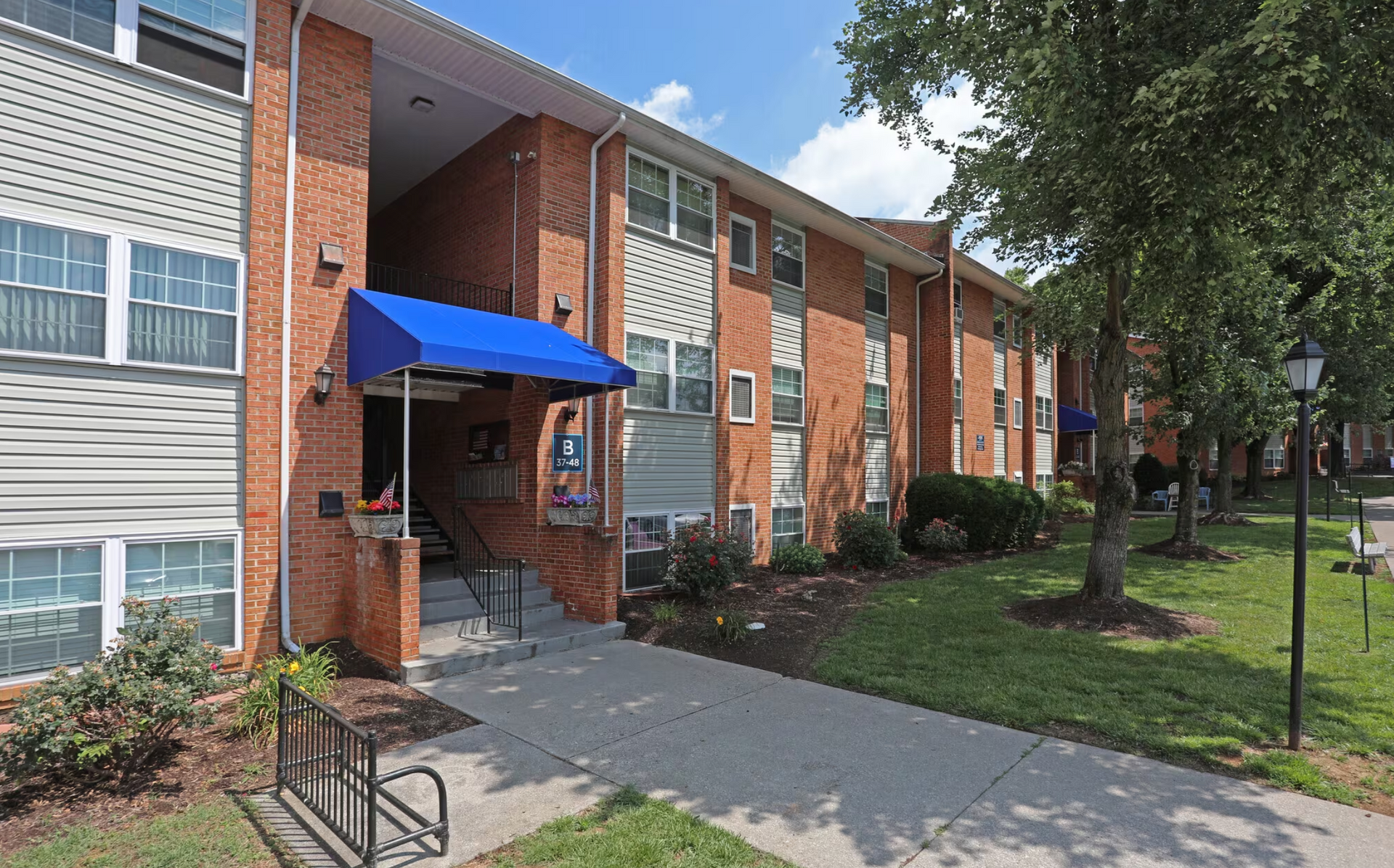 A brick apartment building with a blue awning over the entrance.