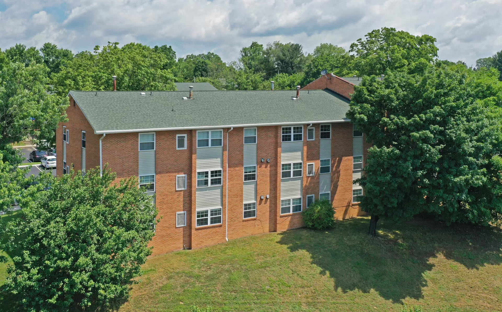 An aerial view of a brick apartment building surrounded by trees.