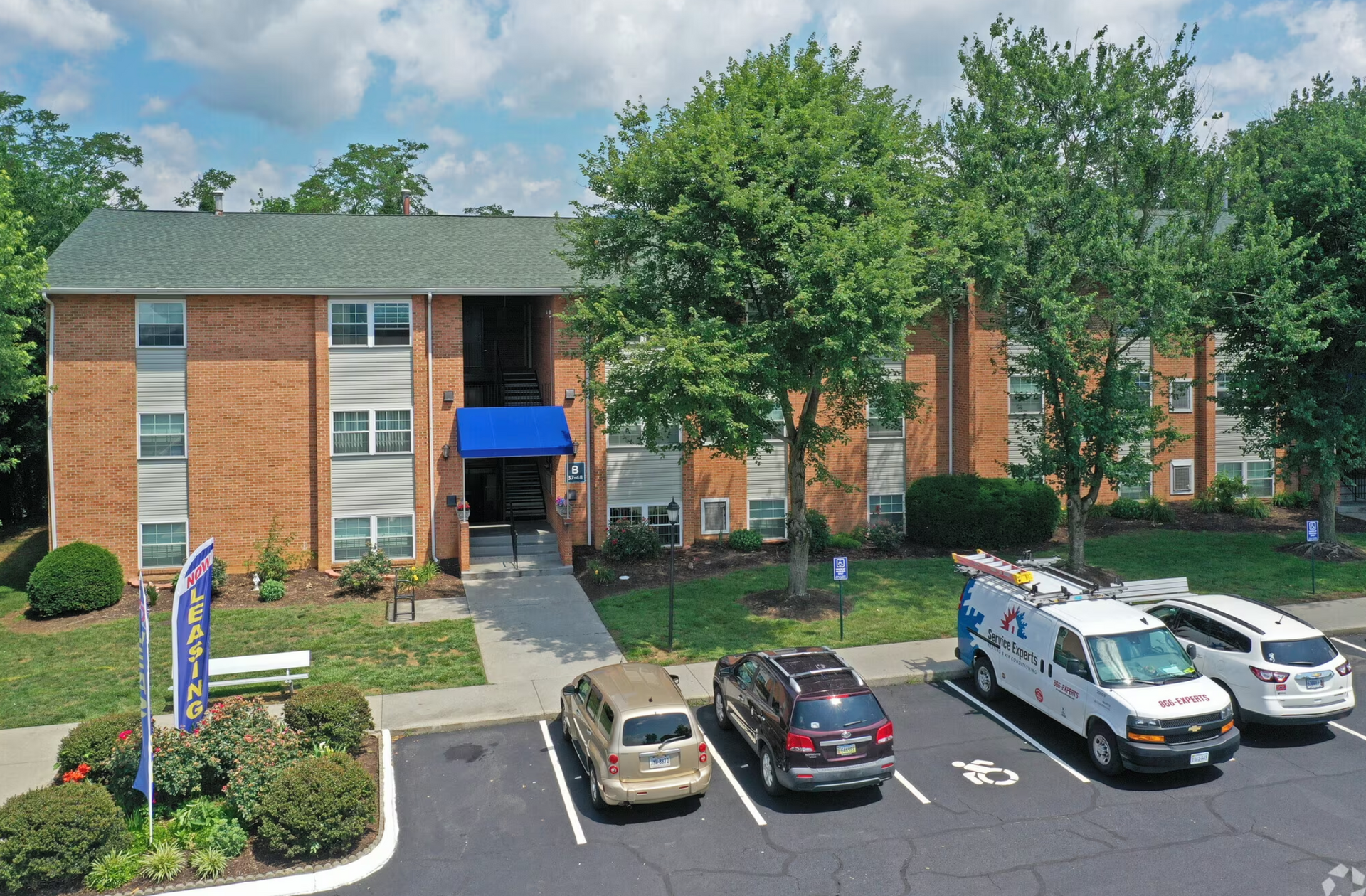 A row of cars are parked in front of a brick building.