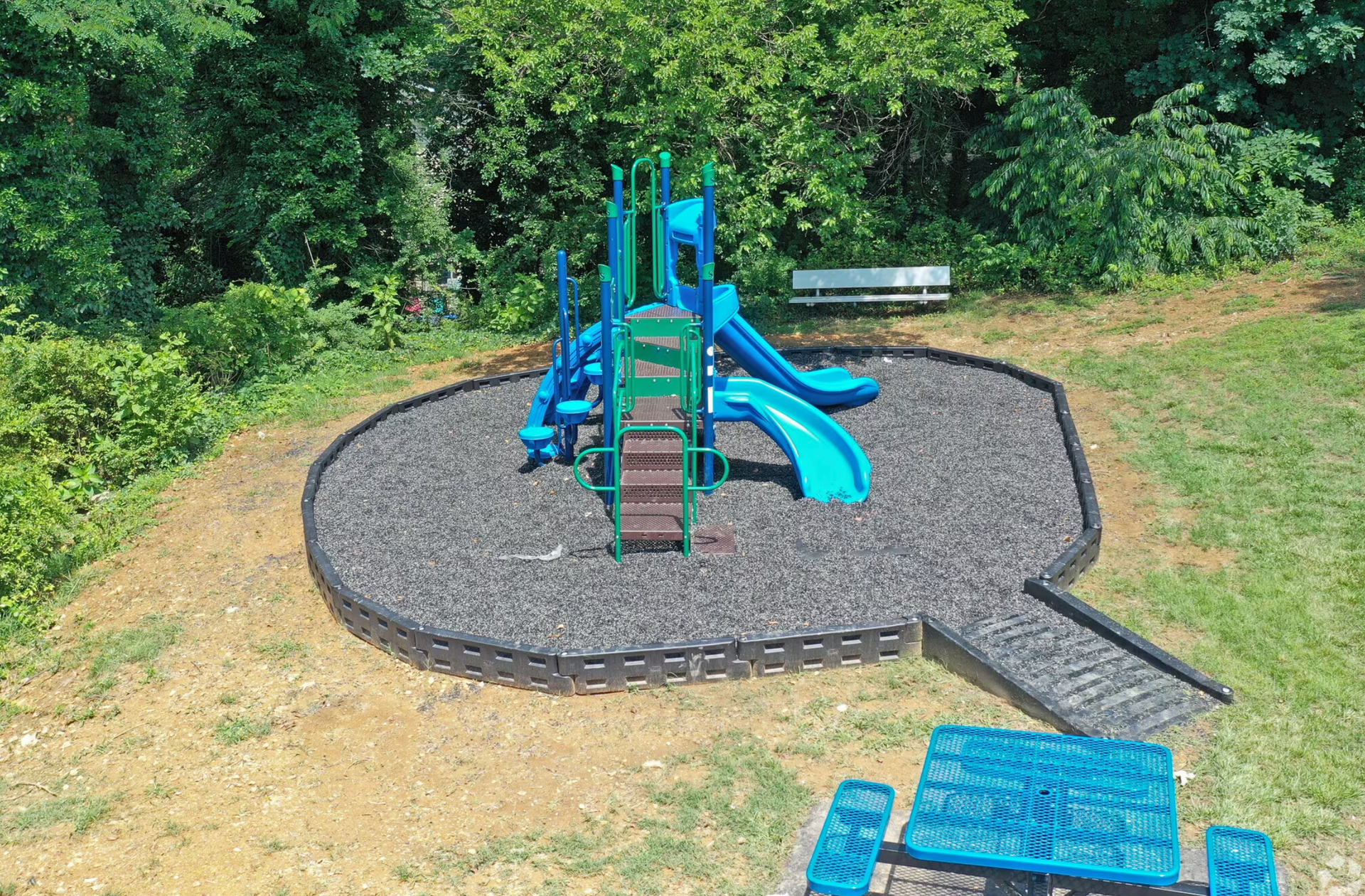 An aerial view of a playground with a slide and a picnic table.