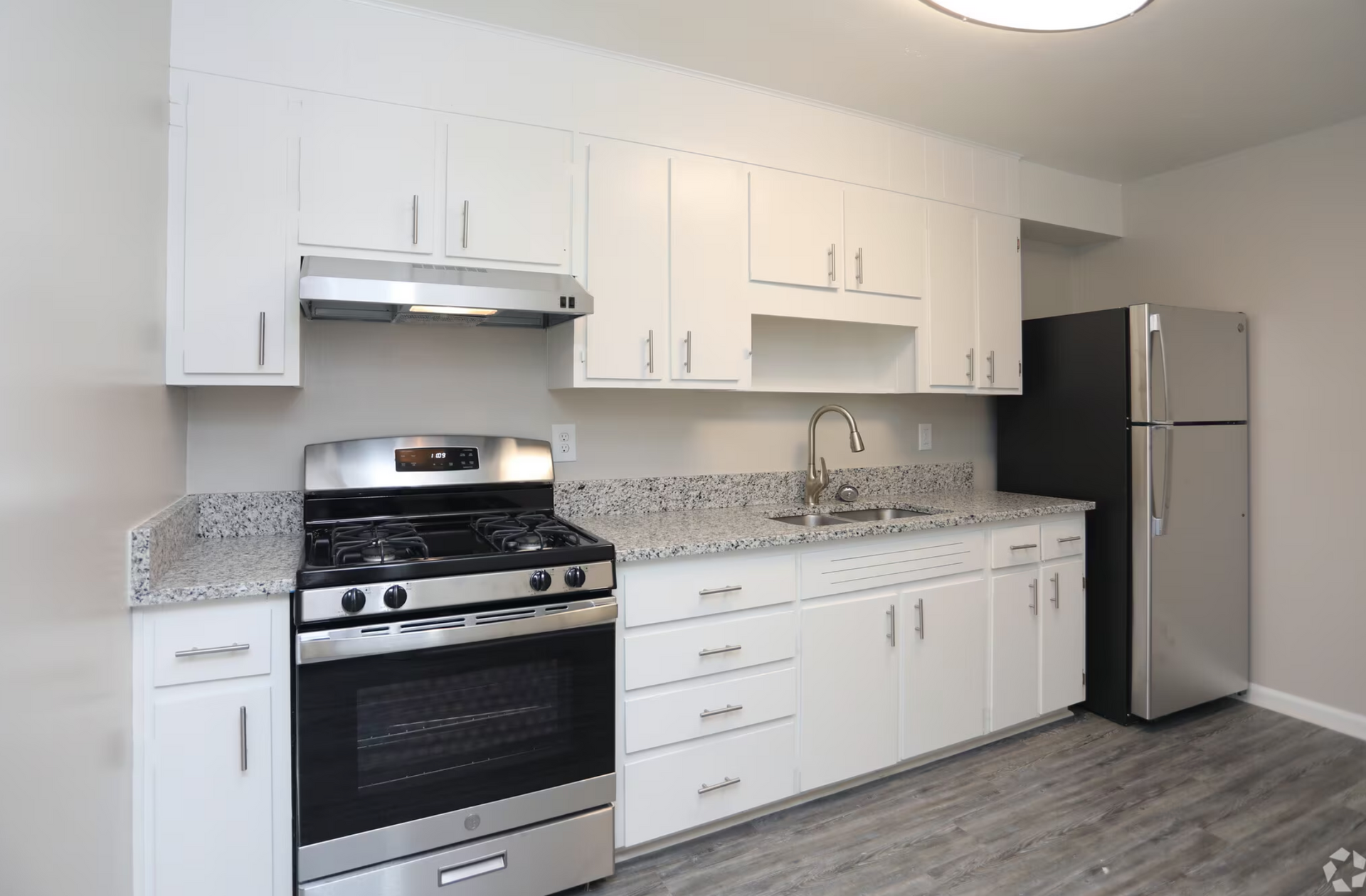 A kitchen with stainless steel appliances and white cabinets.