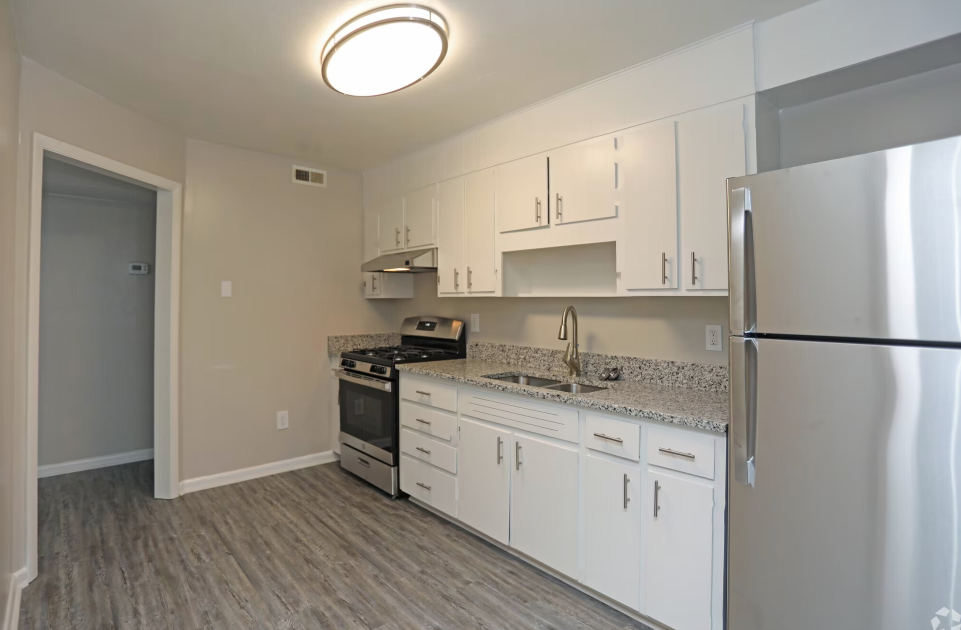 Apartment kitchen with appliances, white cabinets, and a sink.