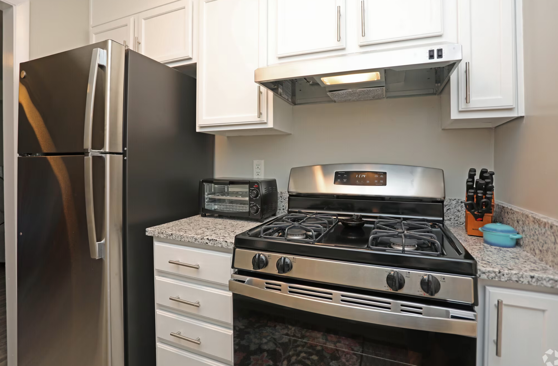 A kitchen with a stove , refrigerator , and toaster oven.