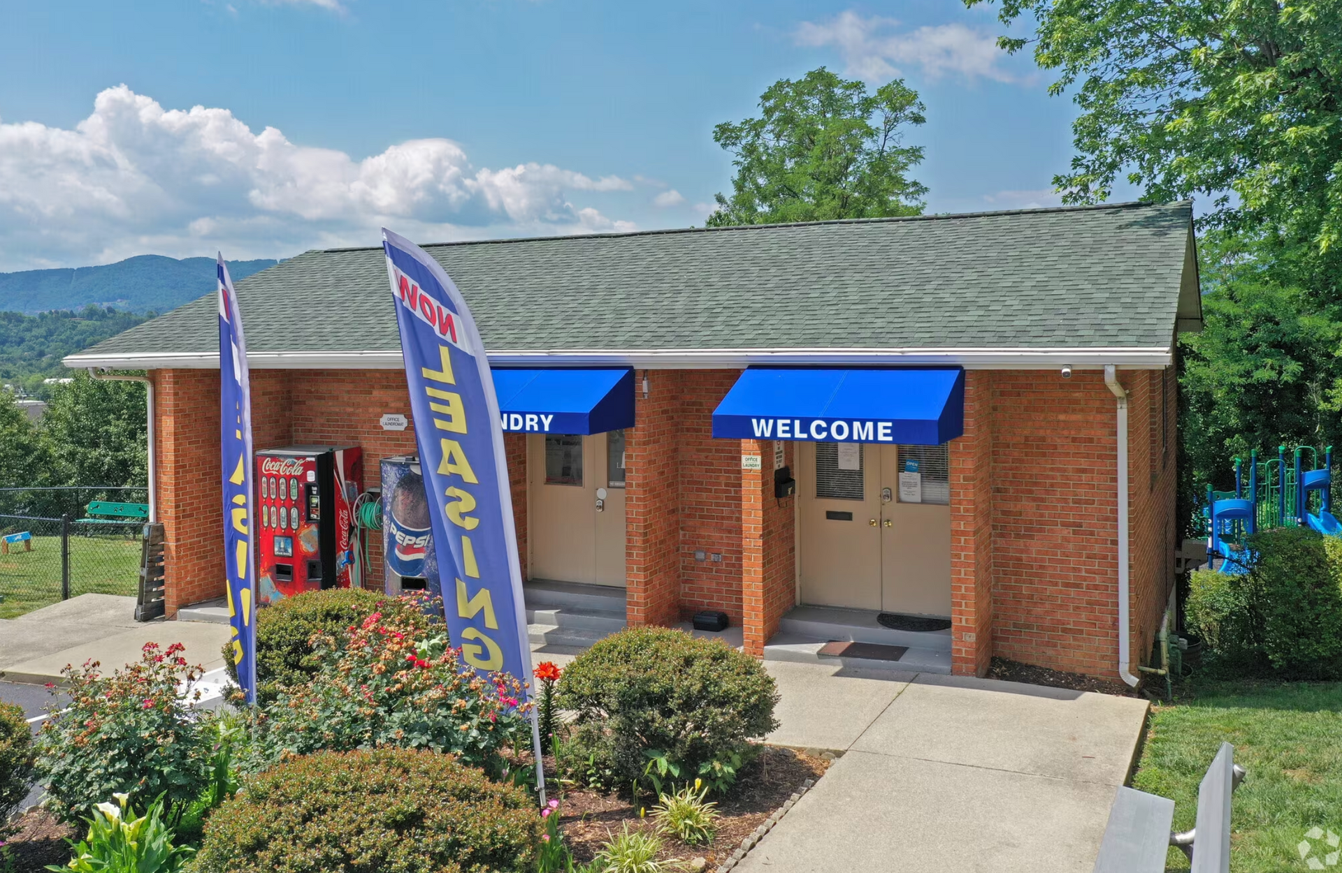 A brick building with a blue awning that says welcome.