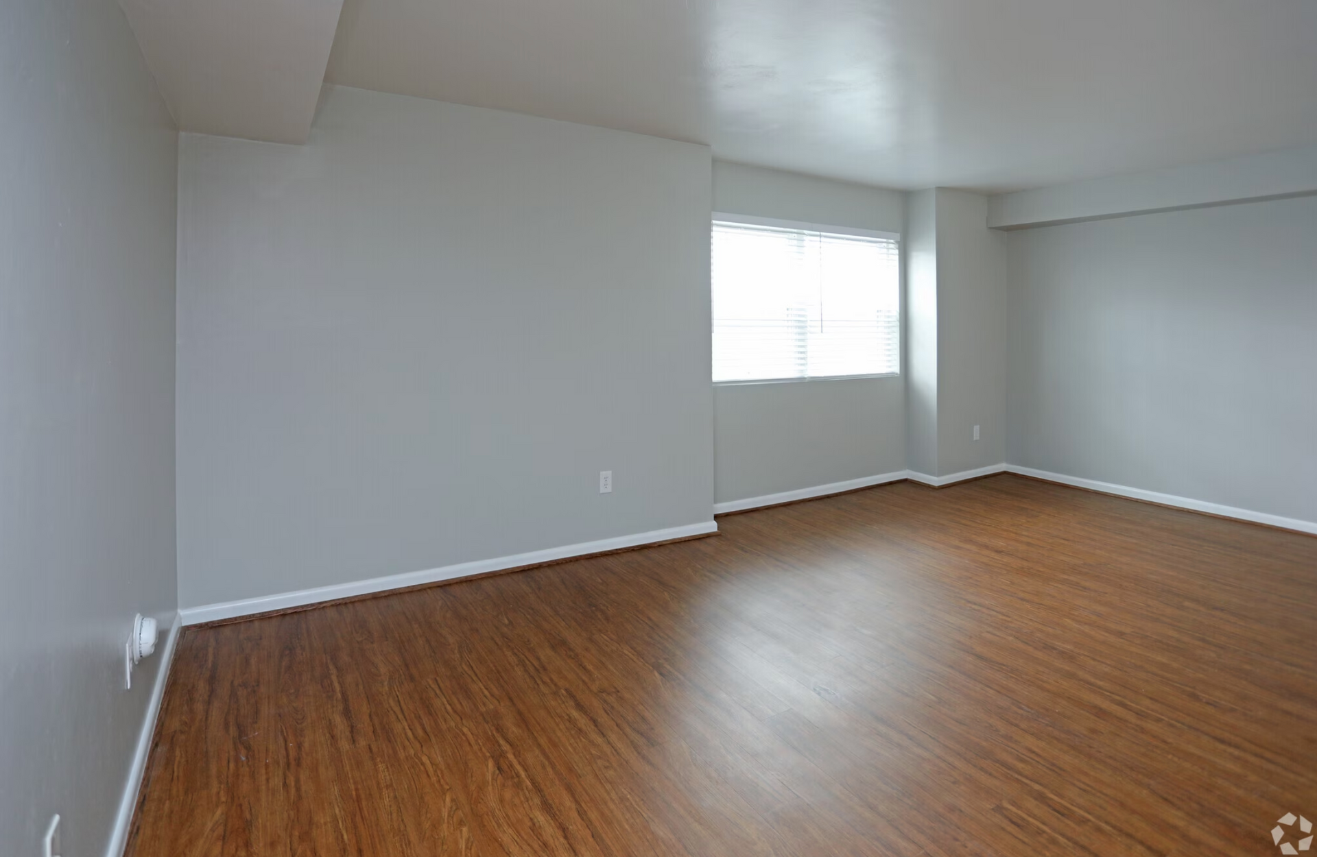 An empty living room with hardwood floors and a window.