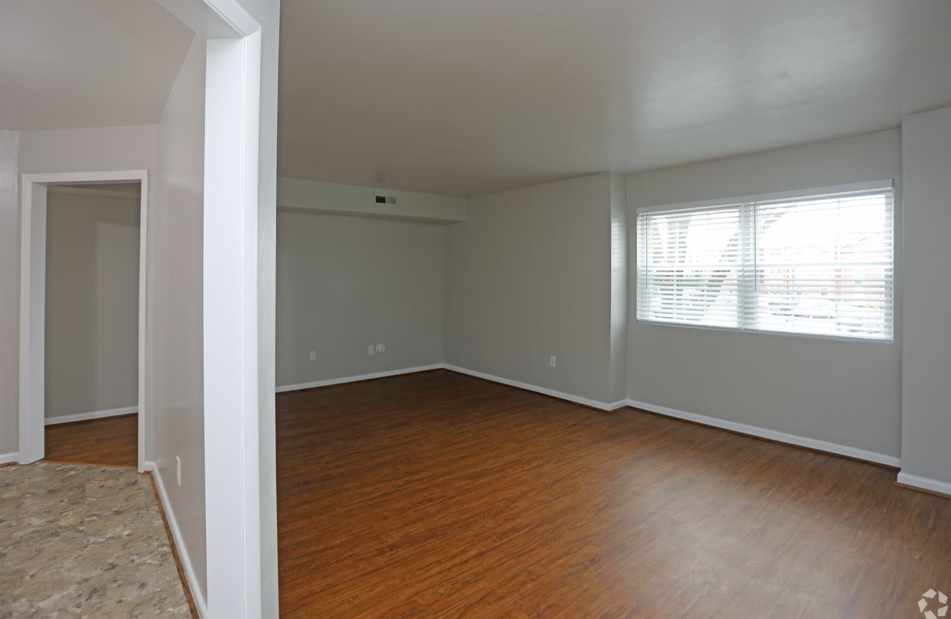 An empty living room with hardwood floors and a window.