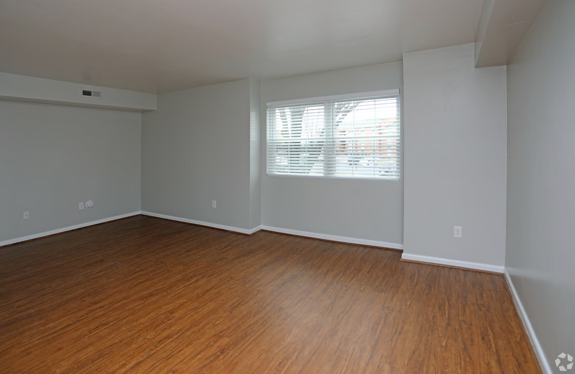 An empty living room with hardwood floors and a window.