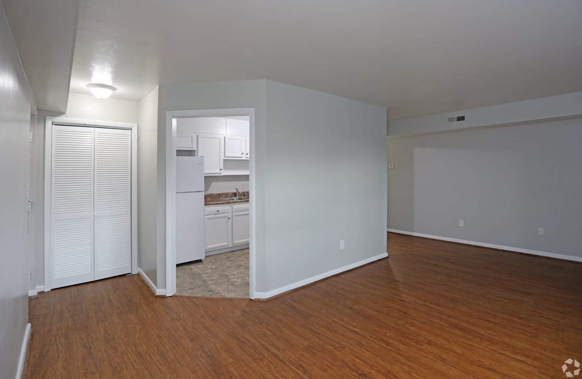 An empty apartment with hardwood floors and white walls.