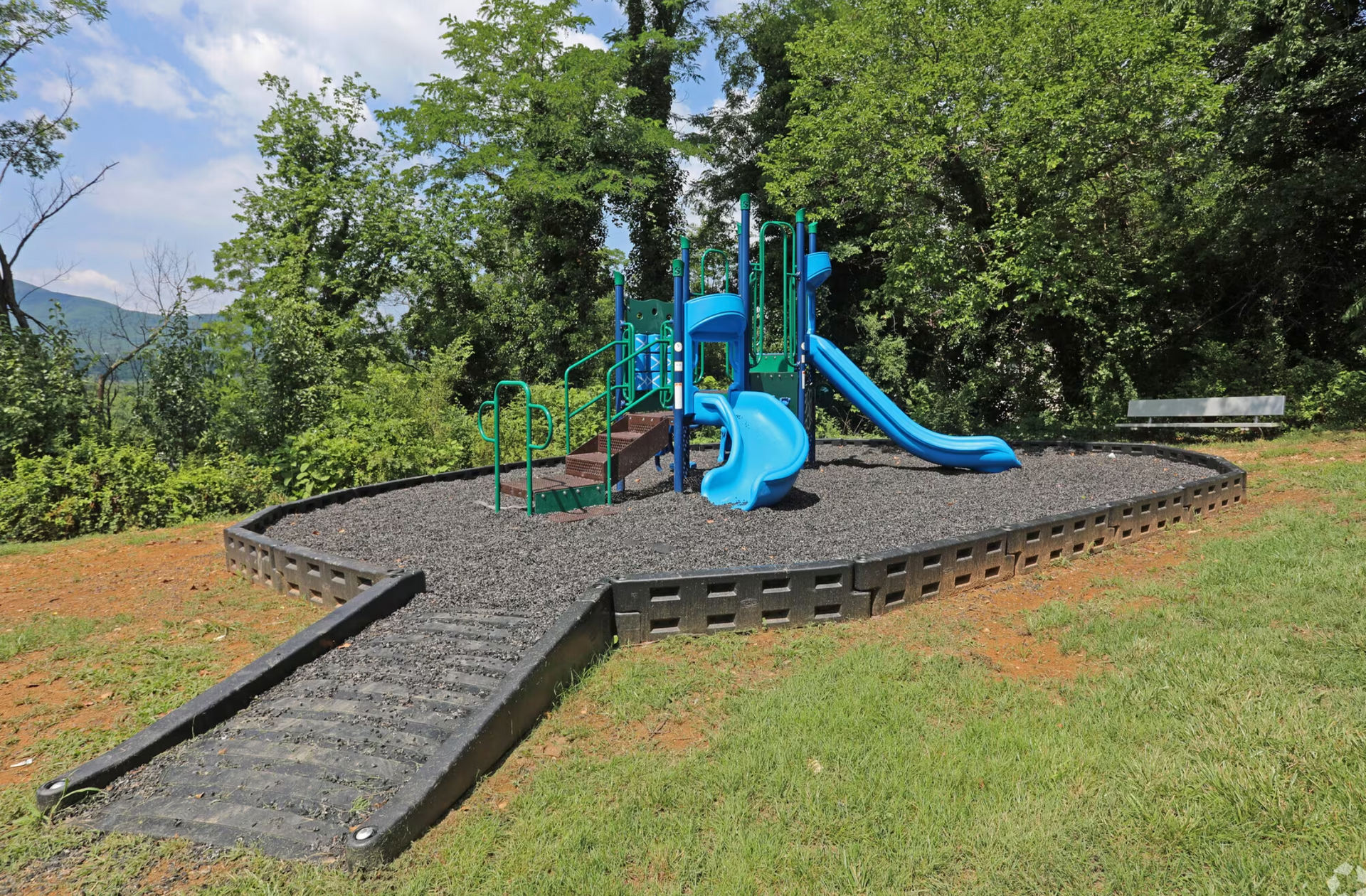 A blue playground with a slide and ramp in a park.