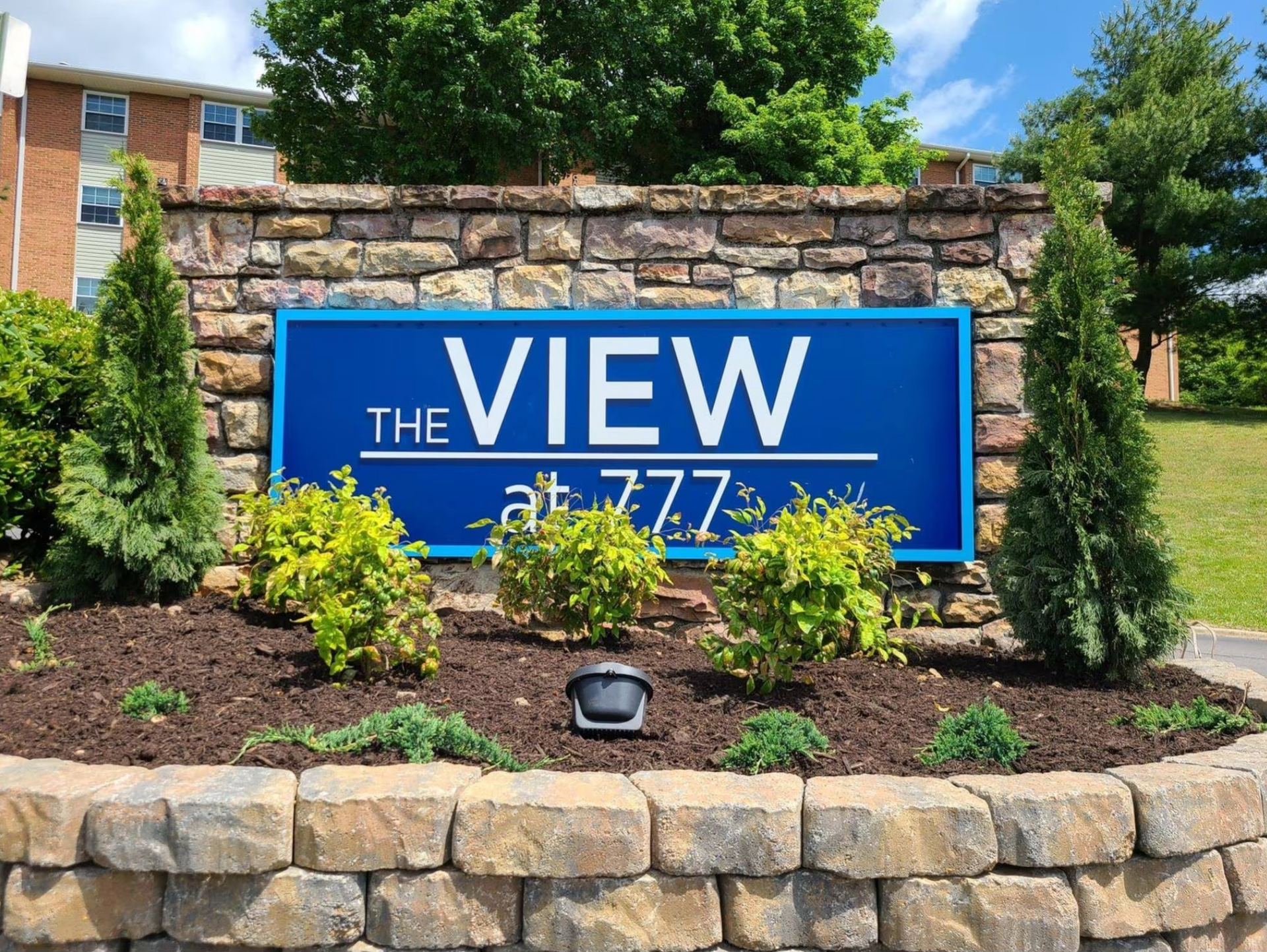 A blue sign on a stone wall says the View at 777.