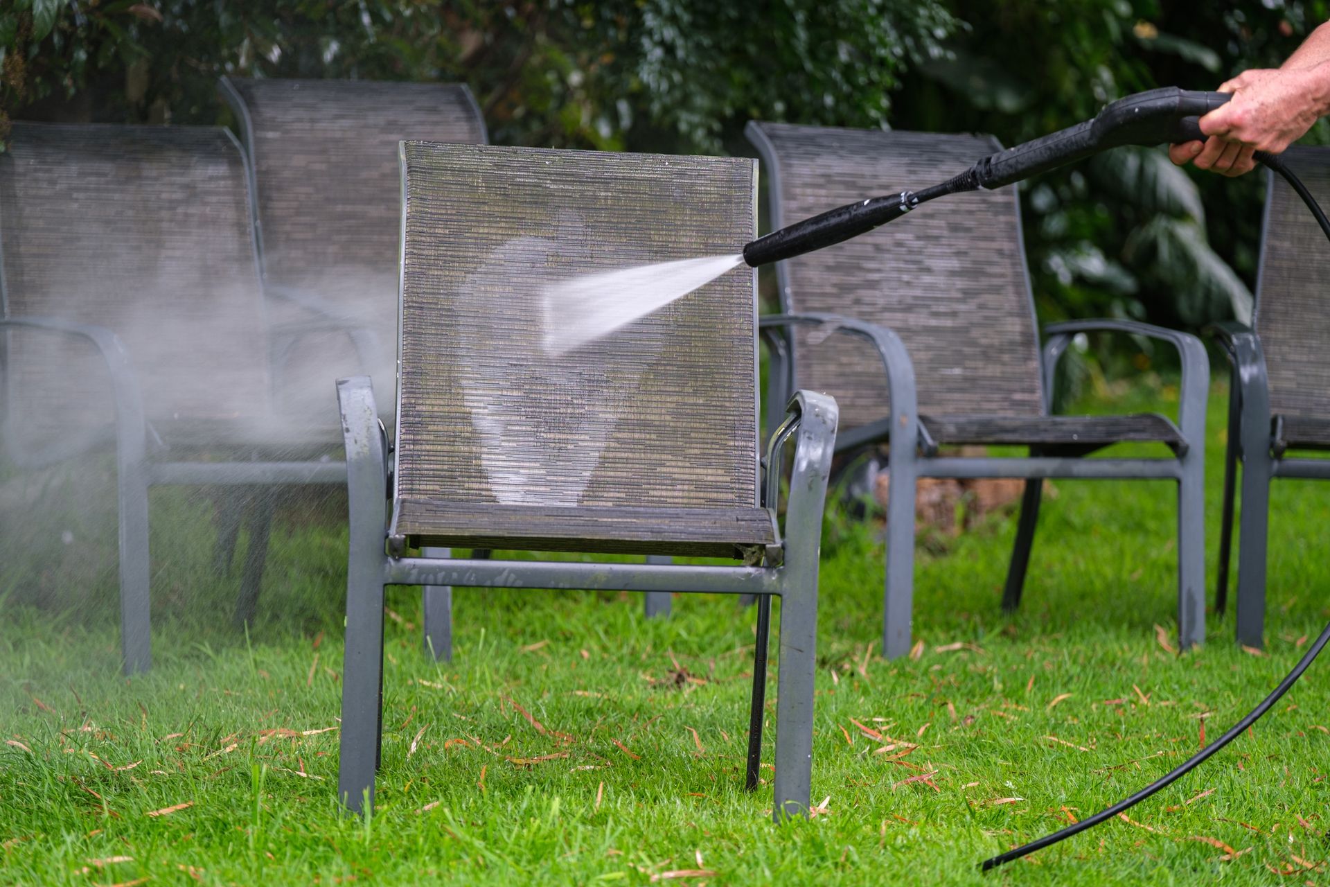 A person is cleaning a chair with a high pressure washer