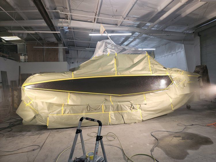 A boat is being painted in a garage.
