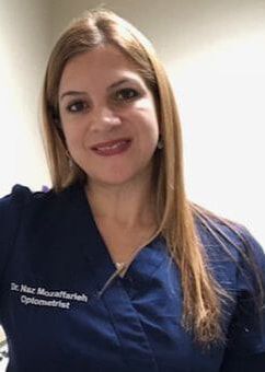 A woman in a blue scrub top is smiling for the camera.