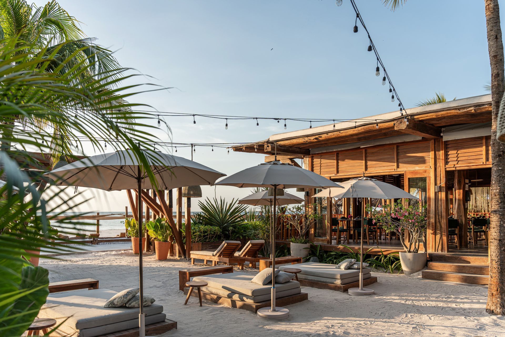 Beachside lounge with sun umbrellas, wooden building, and sand.