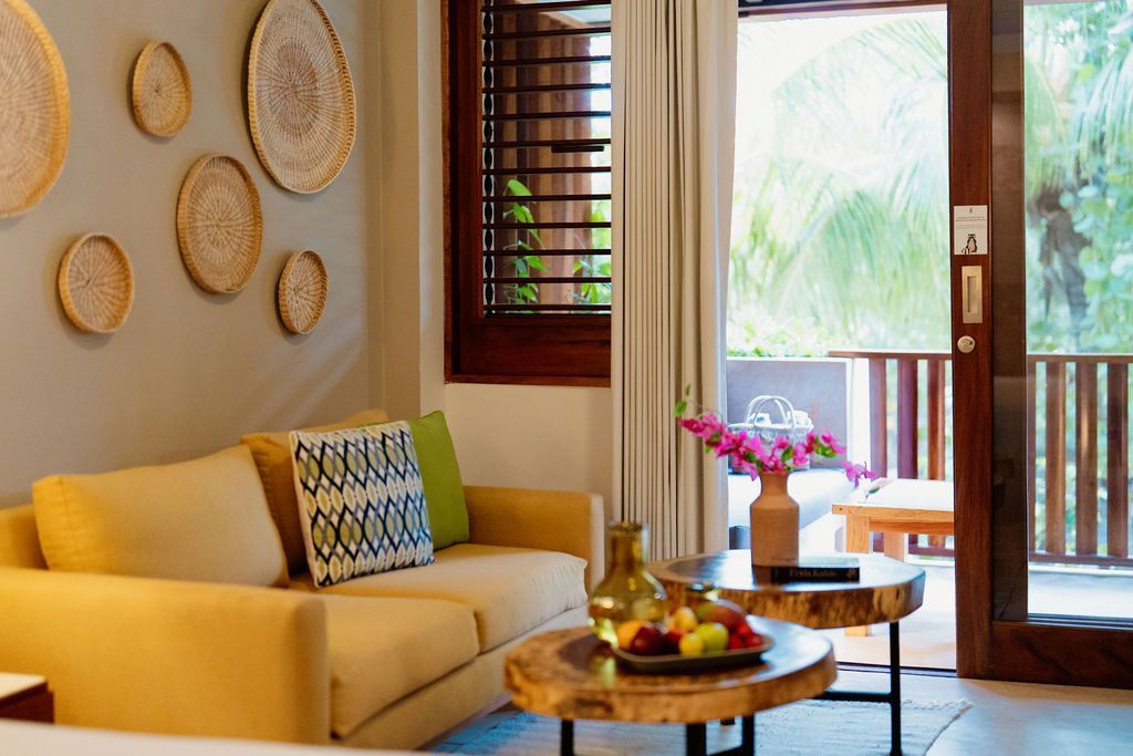Living room with yellow sofa, wood coffee tables, and balcony view.