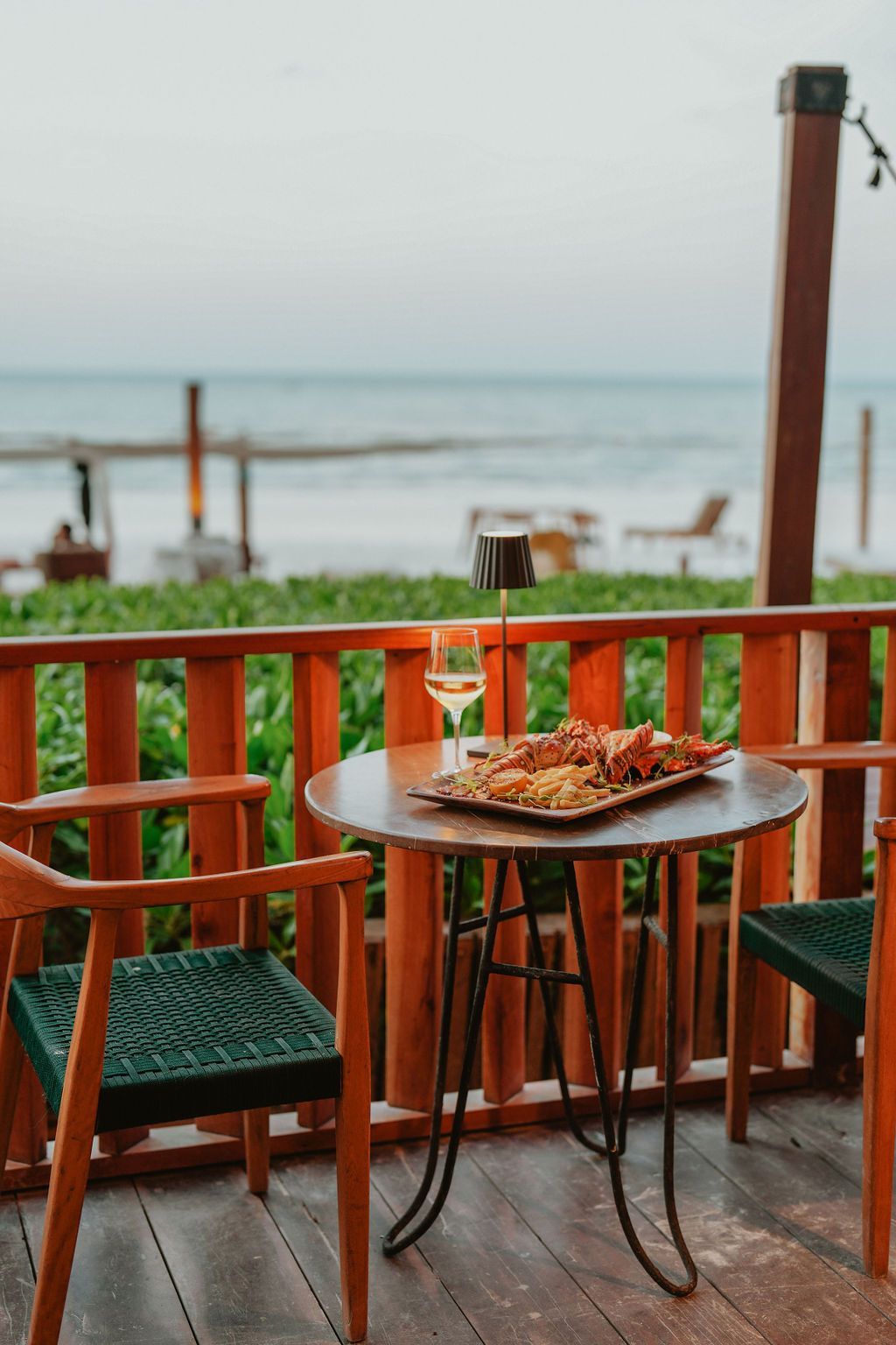 Table set for dining on a deck overlooking the ocean; appetizers and wine are on the table.