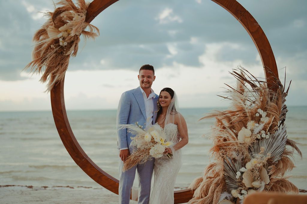 Beach wedding at night with string lights, disco balls, and guests seated.